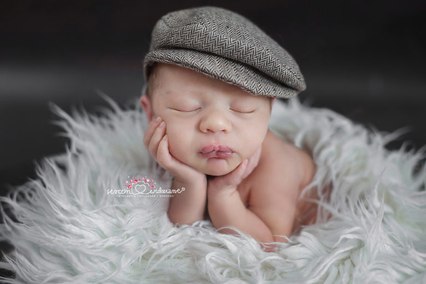 chłopczyk na rączkach na noworodkowej sesji zdjęciowej