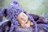 noworodek na sesji w fioletowej czapce misia