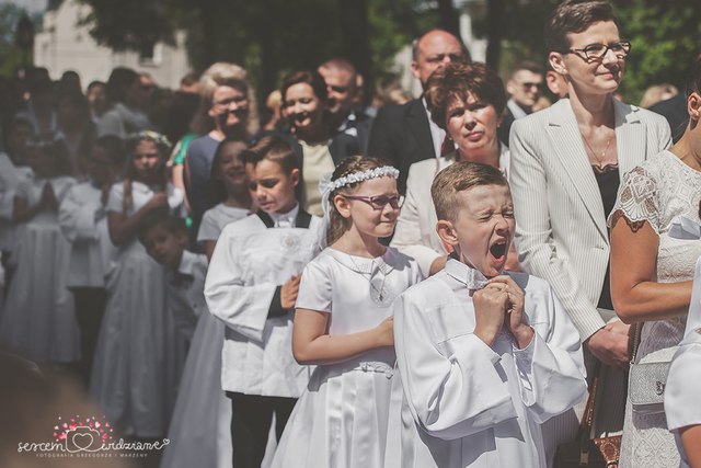 chłopiec czeka pod kościołem na komunii