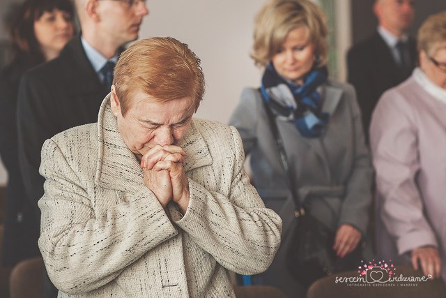 babcia modli się za wnuka na chrzcie
